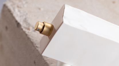 Top of a white perfume bottle, with its lid off, shot from above on a stone background