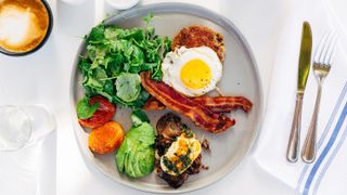 A plate with eggs, bacon, avocados and mixed salad