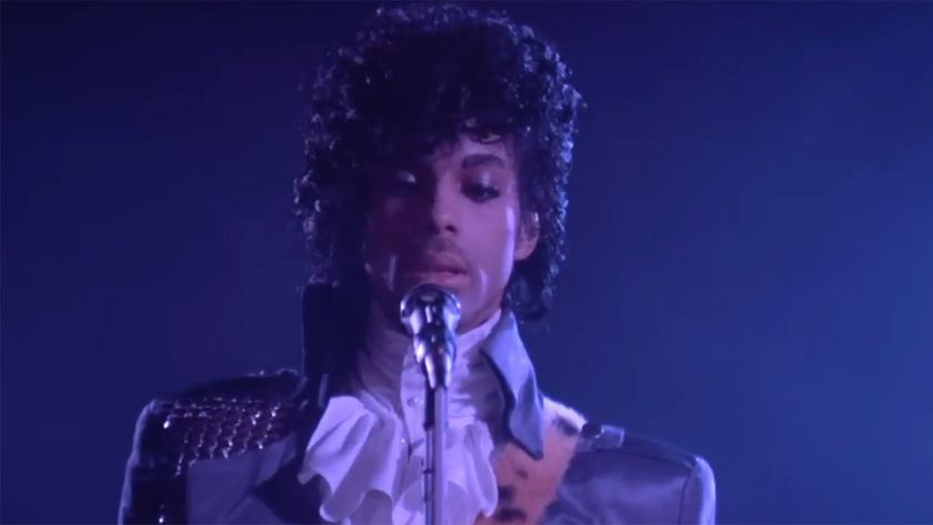 Prince performing in Frilly shirt and purple jacket in purple rain. 