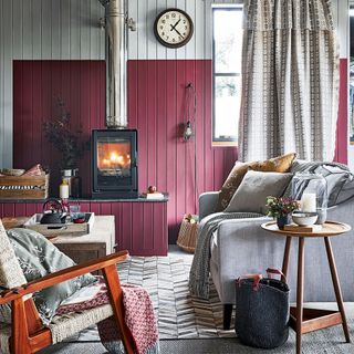 A cosy living room with log burner wooden clad walls painted red and off white