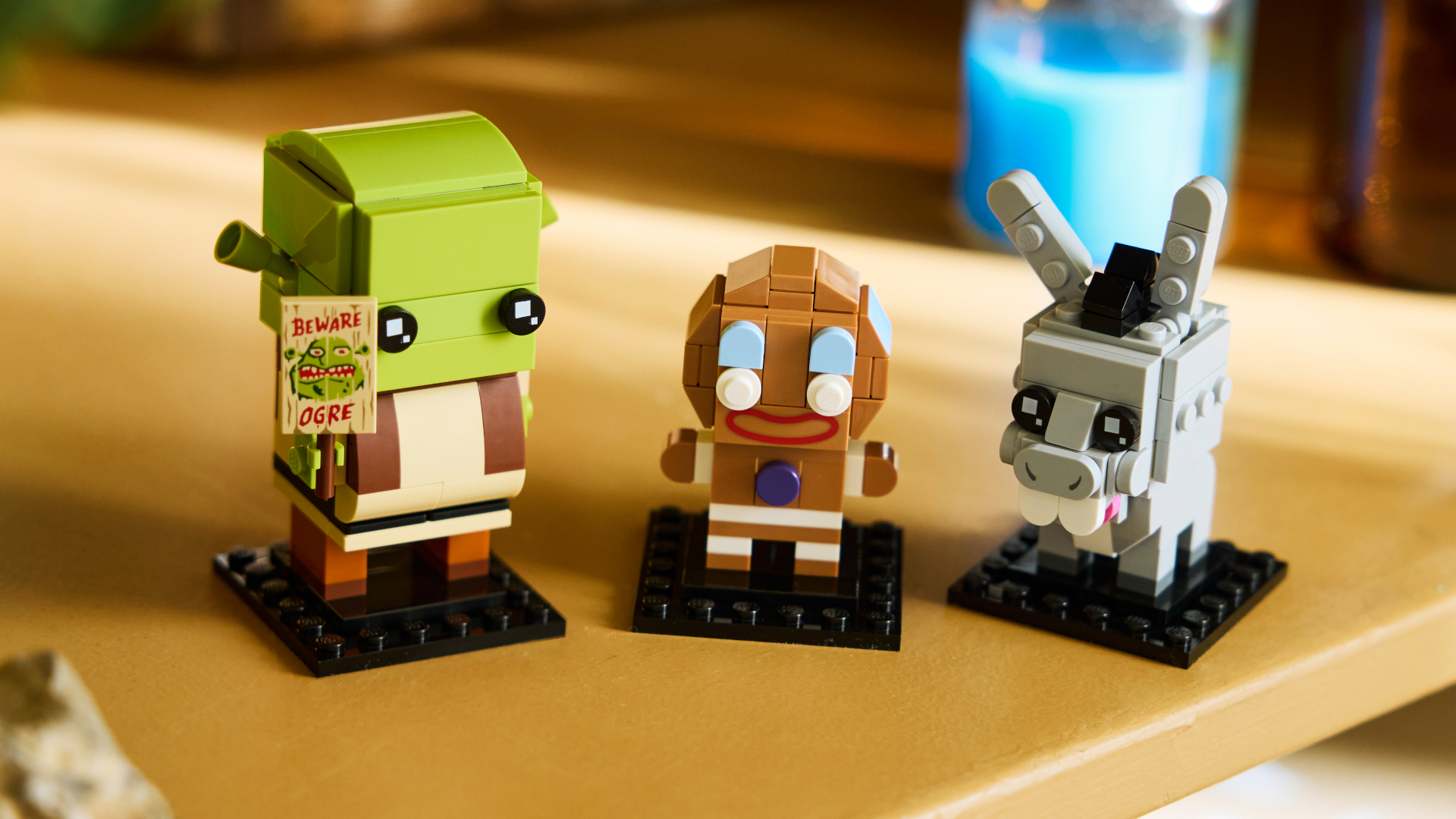 Lego Shrek, Donkey, and Gingy BrickHeadz figures on a wooden table