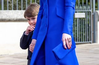 Prince Louis holding Kate Middleton's hand, who is wearing a bright blue coat and holding a blue purse on Easter 2023