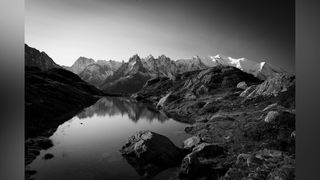 A black-and-white landscape with light settling on Mont Blanc in the background 