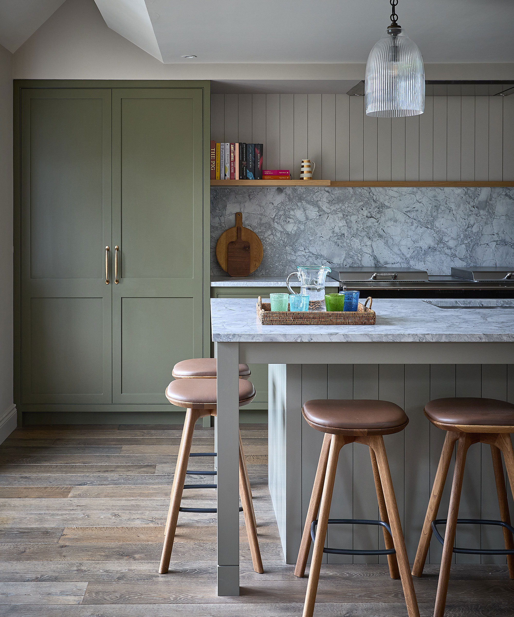 sage green kitchen with island and marble splashback