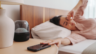 Woman pushing phone away on bedside table