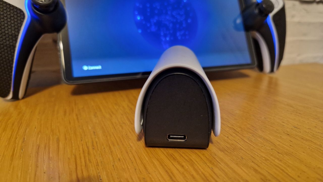 PlayStation Pulse Explore earbuds on a wooden surface with a white brick background
