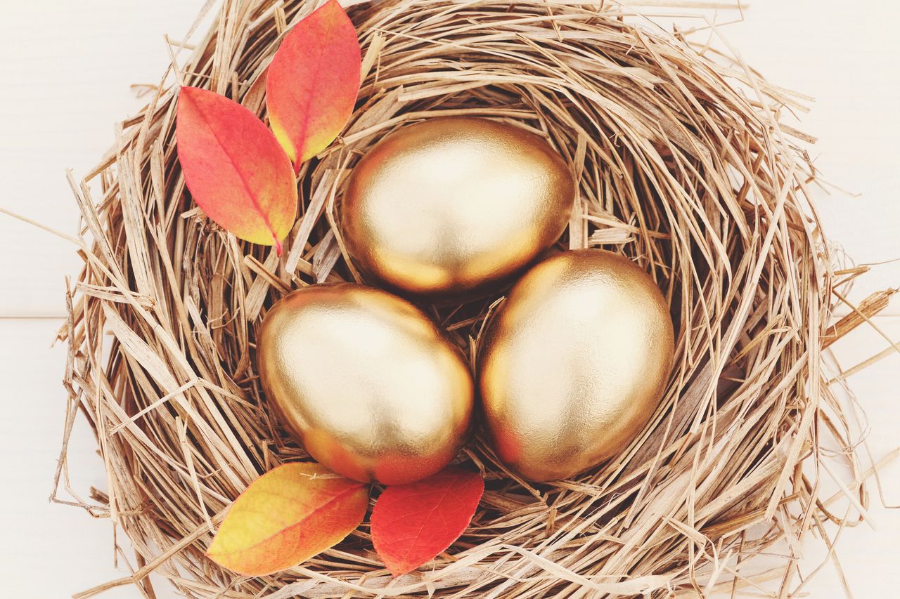 Three gold eggs in a nest with autumn leaves.