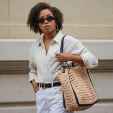 woman wearing button-down shirt, bermuda shorts, and woven bag
