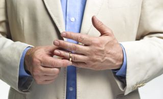A close up of a man taking off his wedding ring