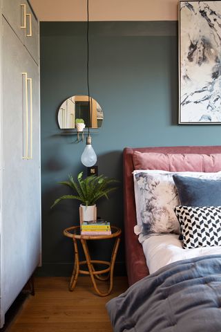 Pink and green bedroom with brass sconce light fittings and pink headboard