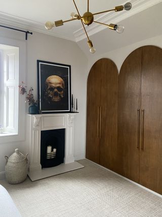 A bedroom with a large wardrobe, a fireplace and arched wooden doors