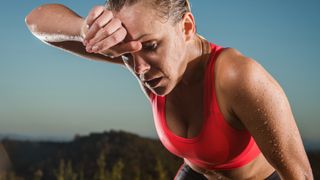 Woman swiping sweat off her forehead after fat burning workout