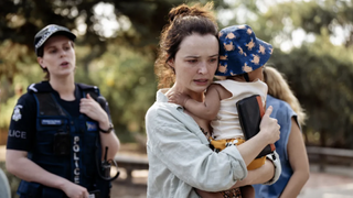 Essie (Philippa Northeast) clutching her baby as a police officer stands behind her in The Family Next Door