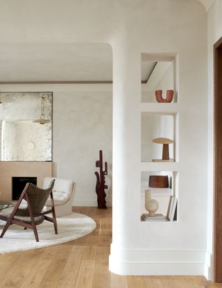 A living room with neutral decor and curved built in shelving