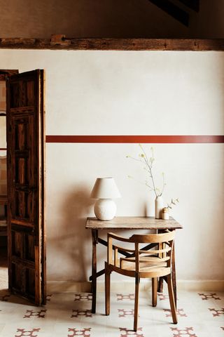 A rustic wooden desk and chair again a wall with a small lamp