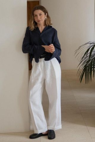 Woman wearing navy shirt and white linen trousers