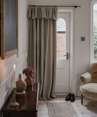 small entryway with a striped front door curtain and cozy chair