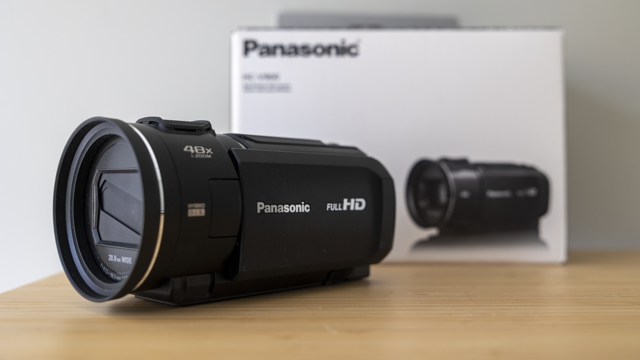 A side view of the Panasonic HC-V900 camcorder on a light wood desk