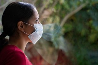 A woman with a face face looking out a window.