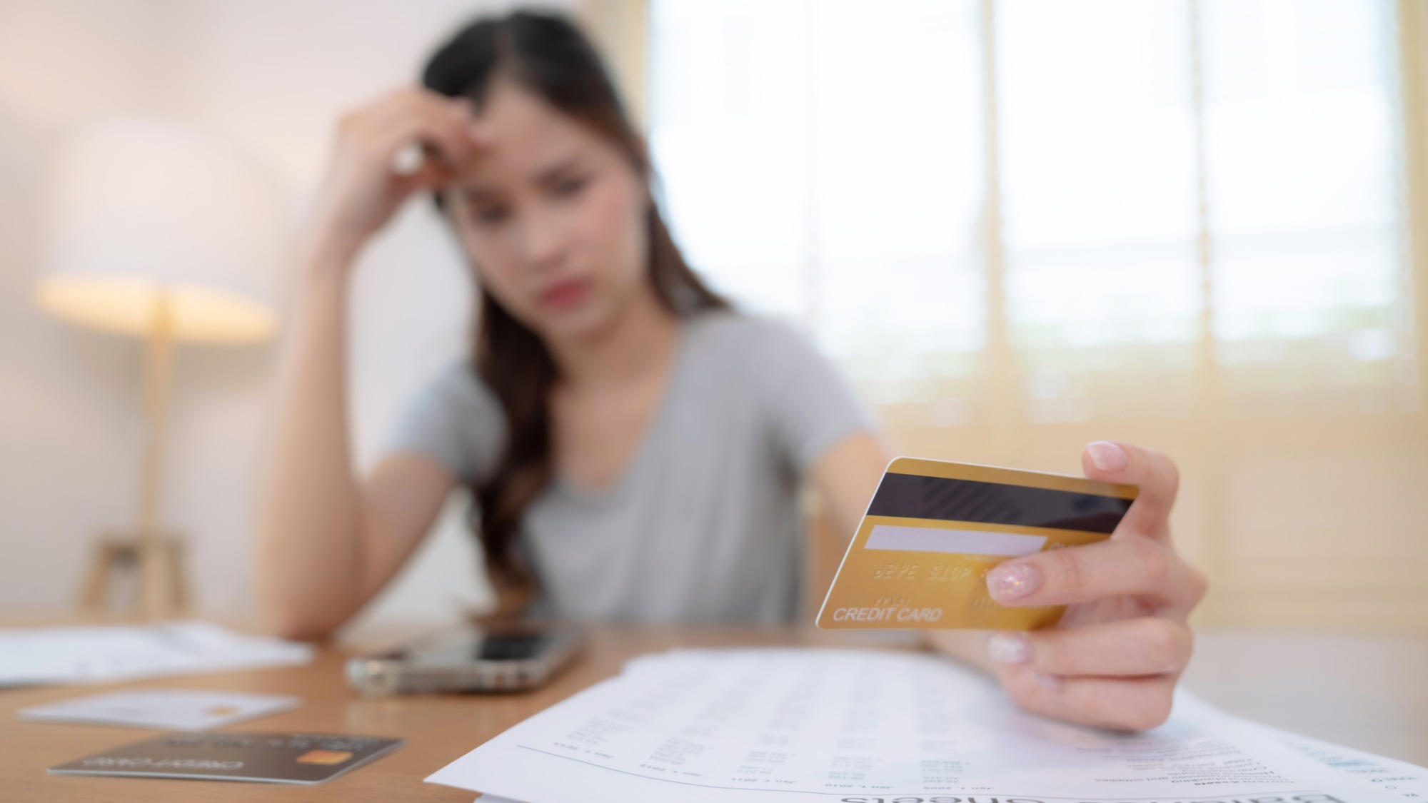 Stressed woman looking at her credit card and monthly expenses
