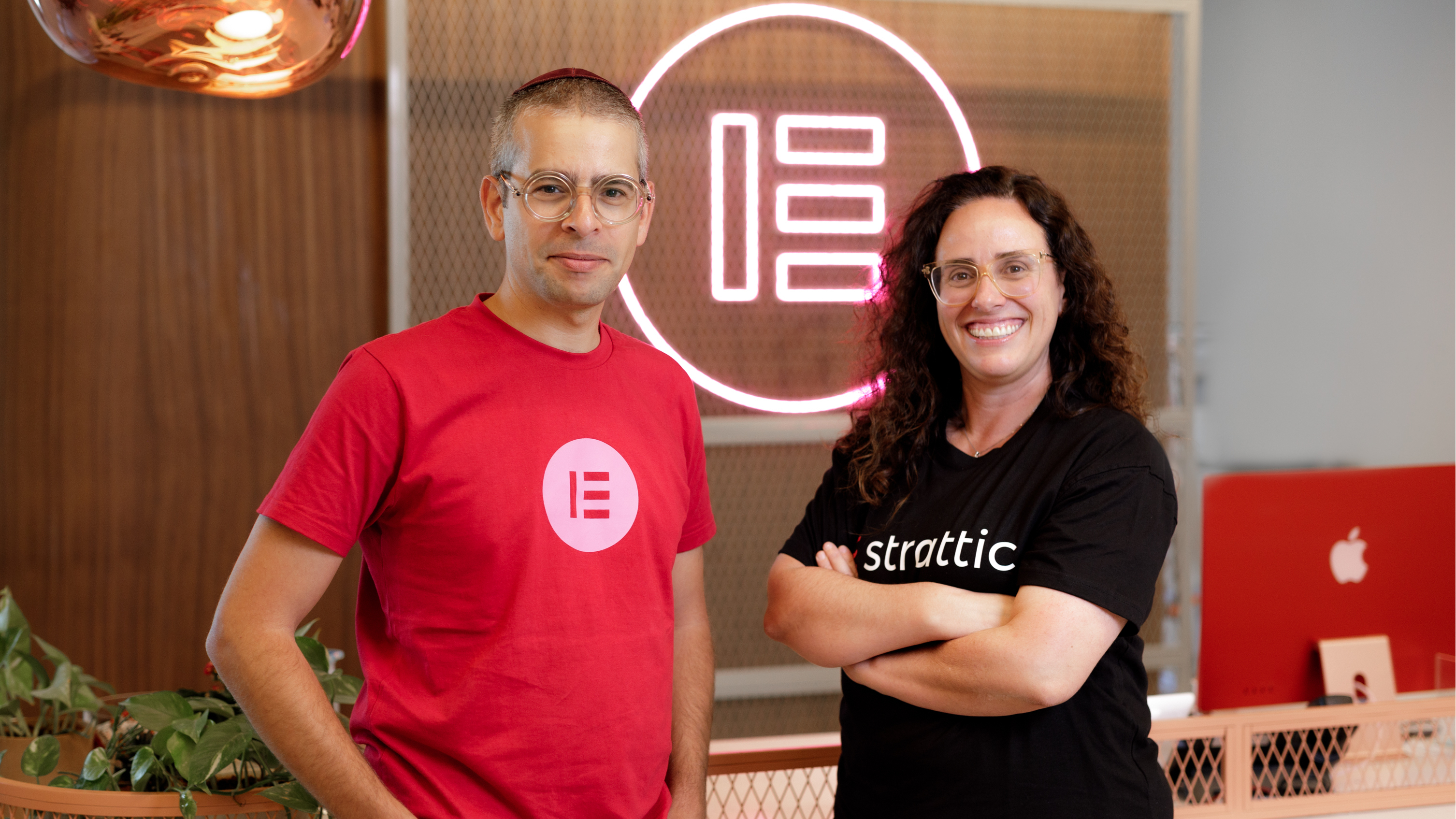 Yoni Luksenberg, CEO of Elementor and Miriam Schwab, CEO of Strattic standing in front of an Elementor sign