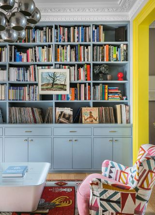 Living room with wall to ceiling bookcase and yellow painted door frame