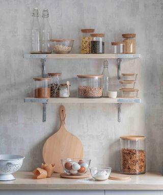 Open shelves in kitchen with rustic shelfie styling featuring glass storage jars and wooden platter