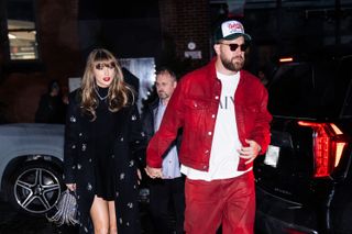 Taylor Swift in a long, crystal-embellished black coat and Travis Kelce, wearing red pants and a matching red jacket, while out in New York City on December 28, 2024