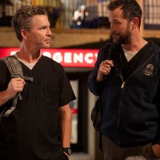 Two doctors look at each other while holding their backpack straps, as they leave an emergency room at night, in 'The Pitt.'