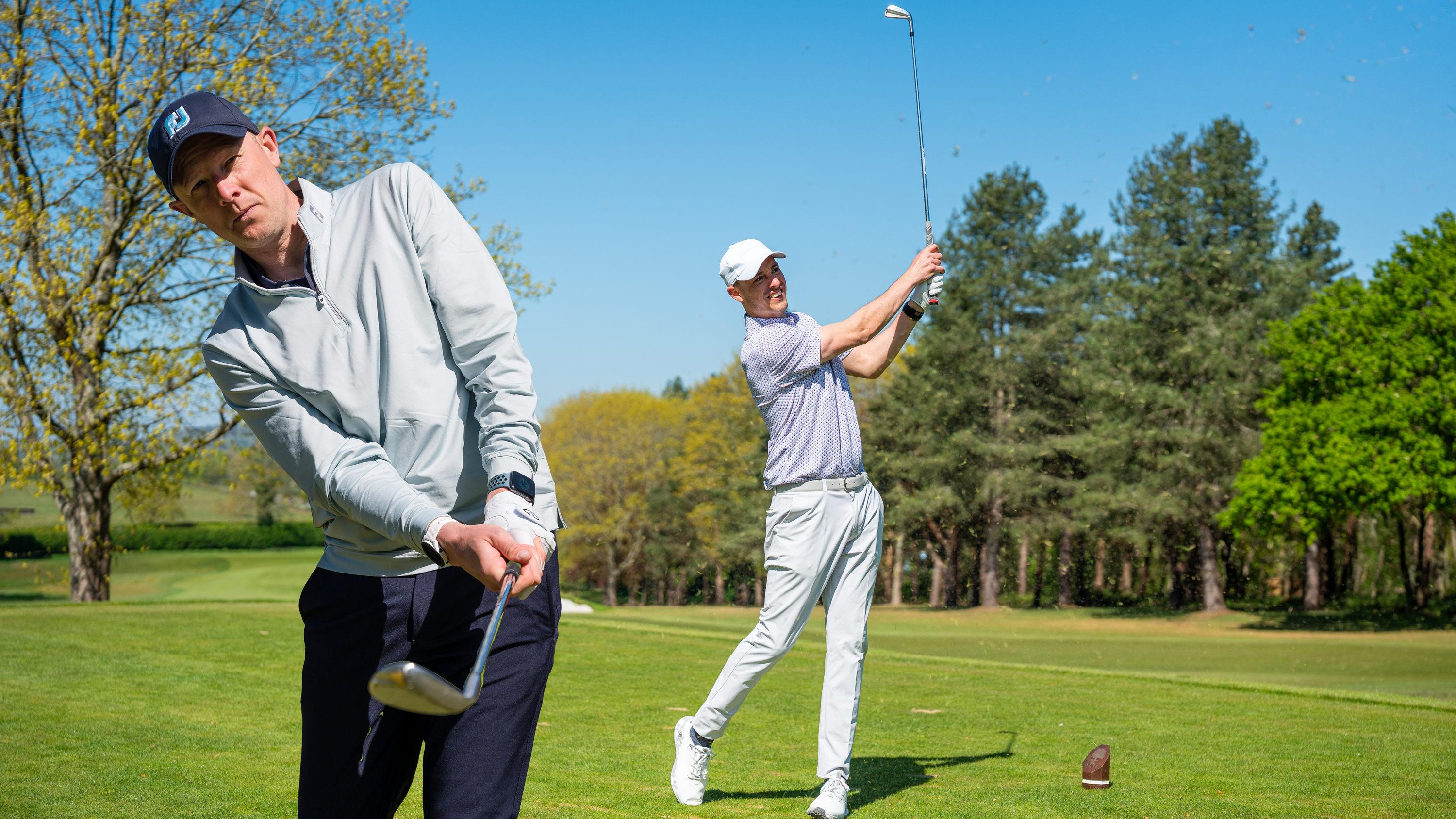 two amateur golfers hitting a pitching wedge on the golf course