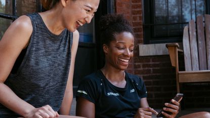 Two fit women working out how to use Strava on their phone