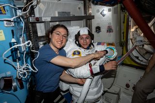 NASA astronaut Christina Koch (left) poses for a portrait with fellow Expedition 61 Flight Engineer Jessica Meir of NASA who is inside a U.S. spacesuit for a fit check for a spacewalk on Oct. 18, 2019. It will be the first all-female spacewalk in history.