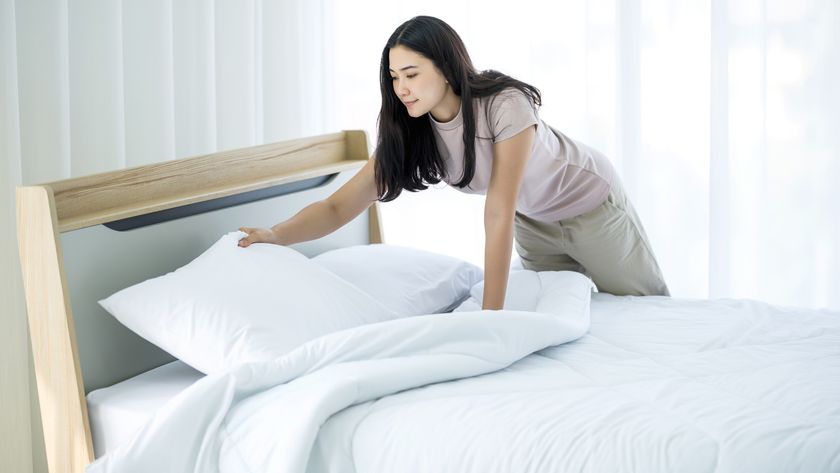 A woman with dark hair stacks pillows on a bed to sleep upright