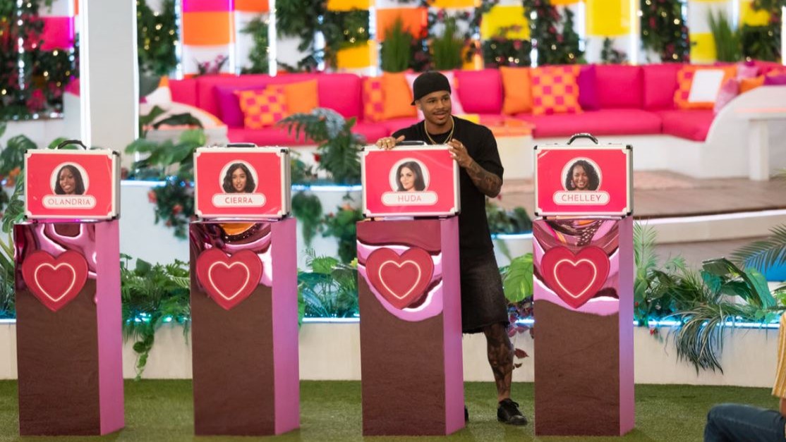 Ace standing behind a photo of Huda in Love Island USA season 7
