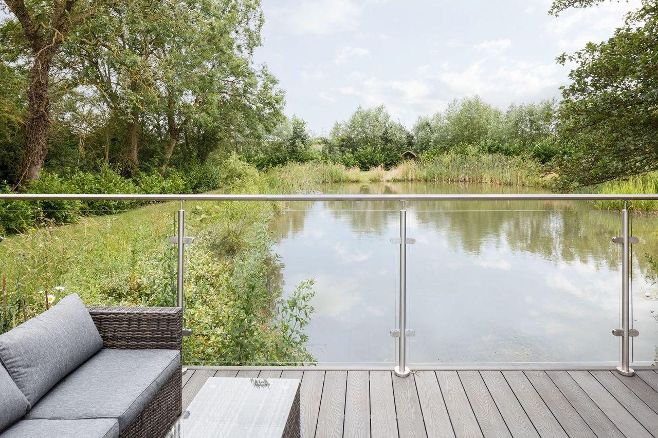 Decking overlooking the pond outside that is glass panelled