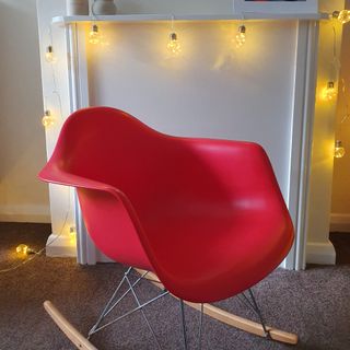 A second-hand red rocking chair with second-hand string lights