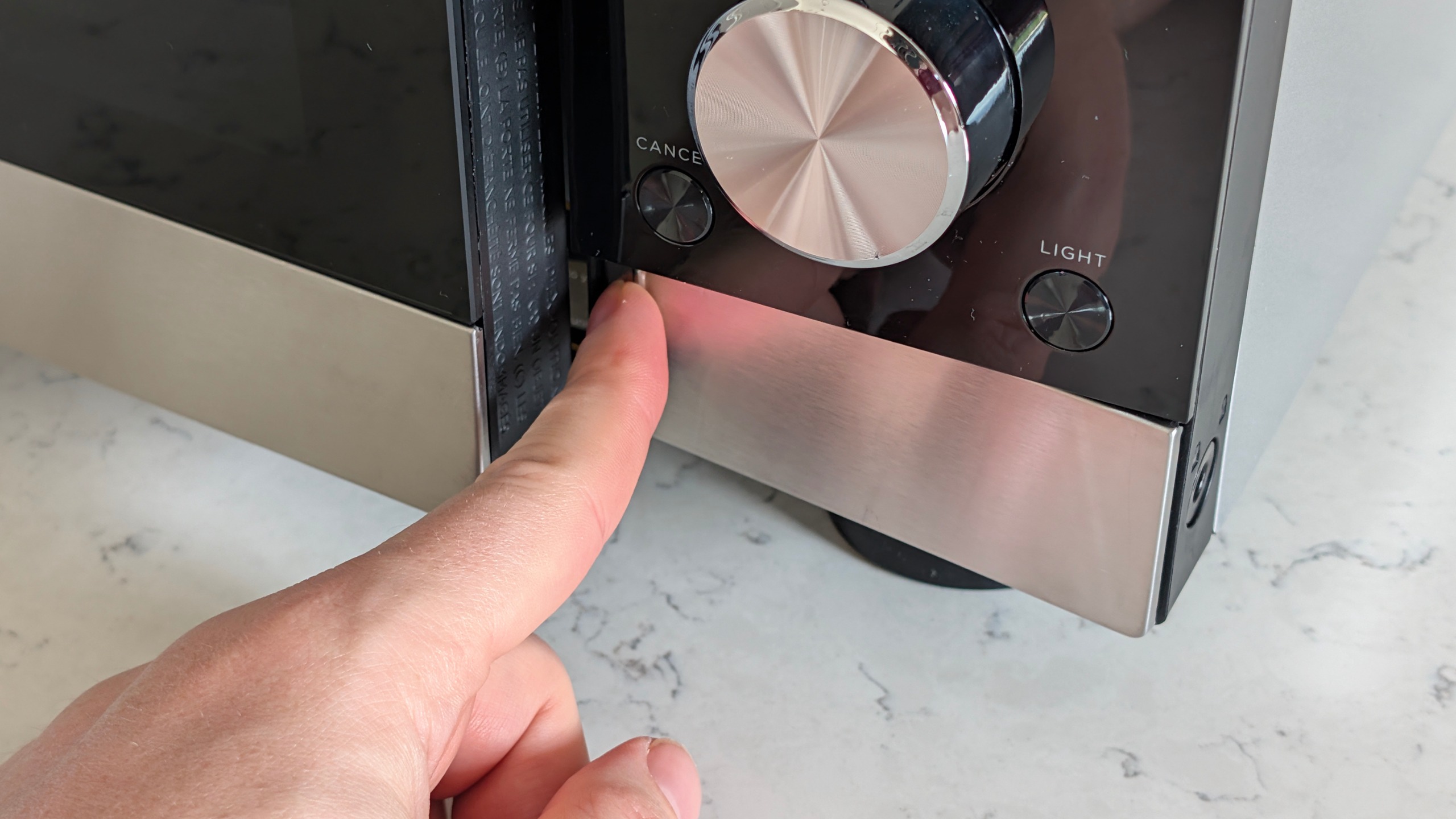 Person pressing Ninja Crispi Microwave open button