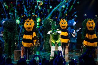 Cricket performing on stage with bees. Cricket is doing a heart shape with his hands to the crowd.