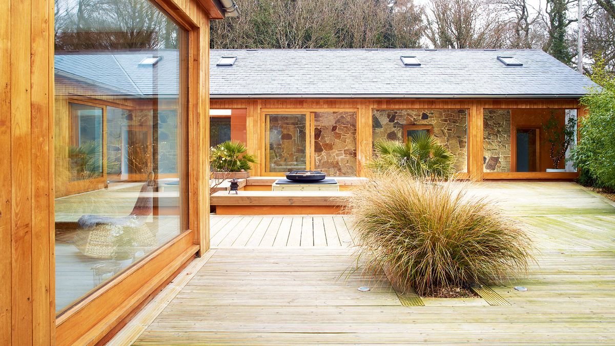 A decked outdoor area in front of a converted barn home and contemporary annexe