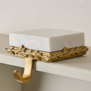 Marble and Gilded Stocking Holder on a white mantel.