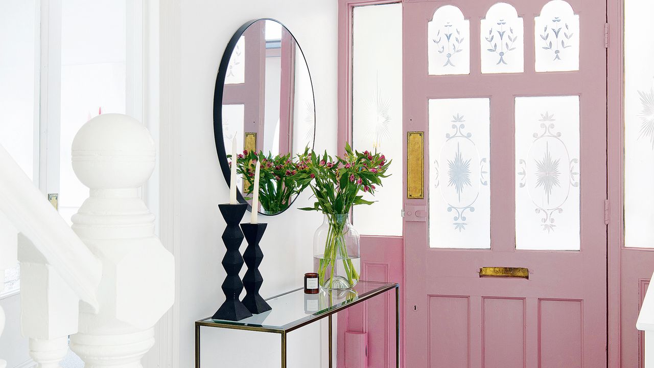 Hallway with pink door and round mirror