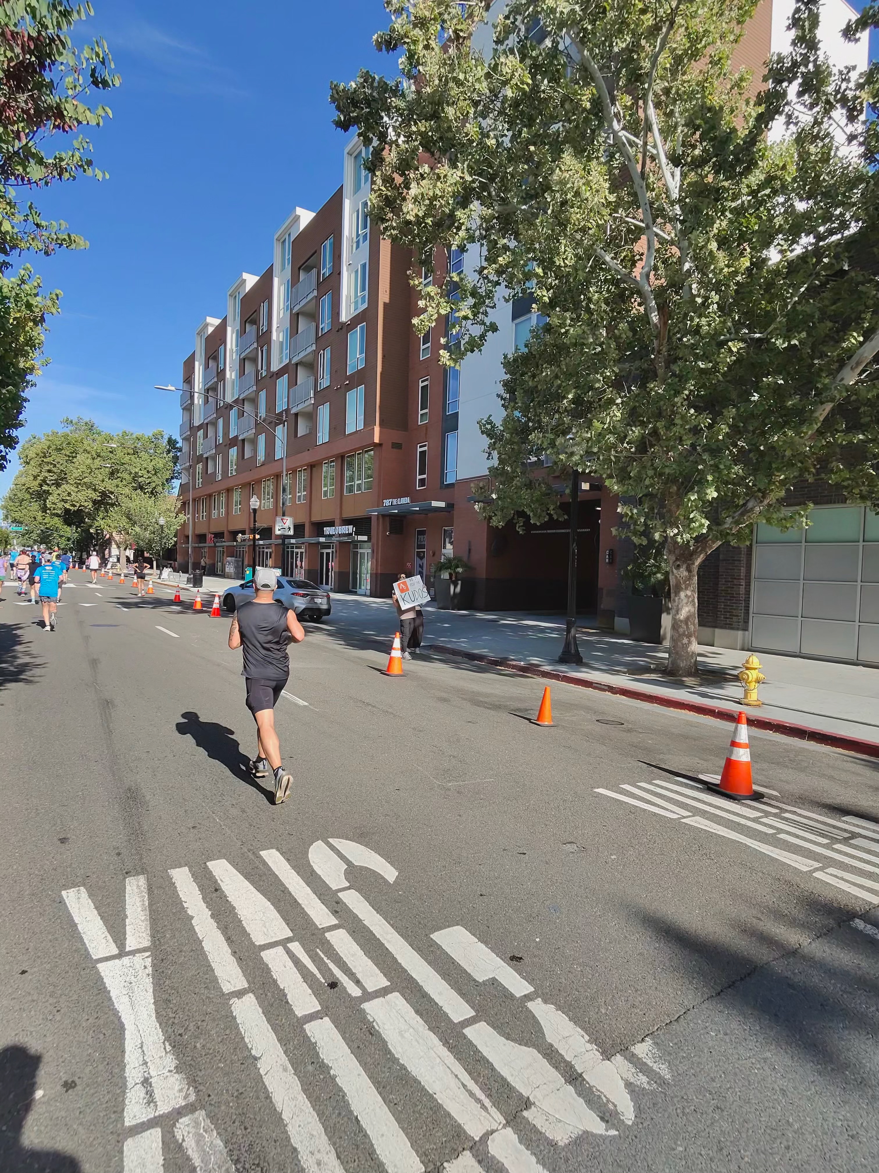A Ray-Ban Meta smart glasses camera sample at the San Jose Half Marathon showing a person holding a funny Strava sign along the edge of the course.