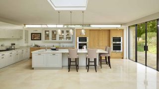 White kitchen island with high-backed pale pink seating in wide kitchen