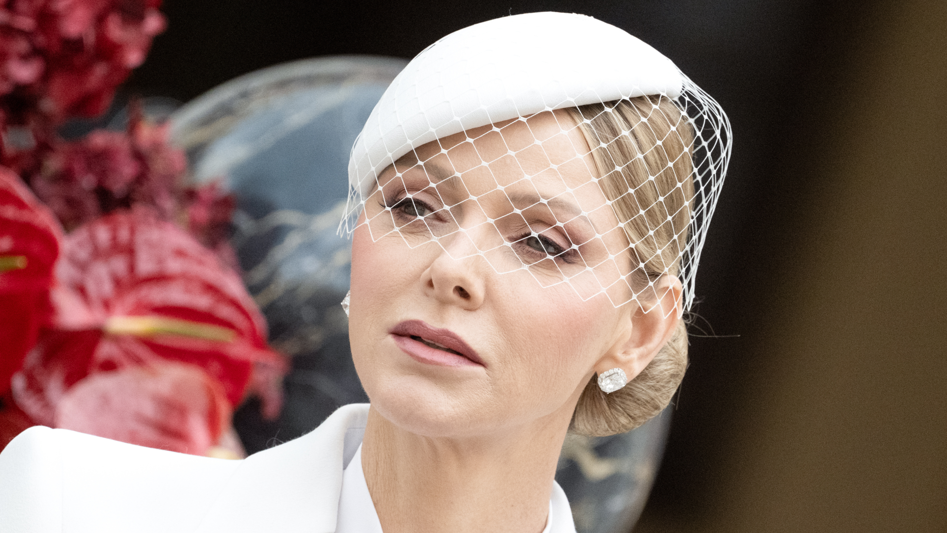 Princess Charlene wearing a white veiled hat and white suit