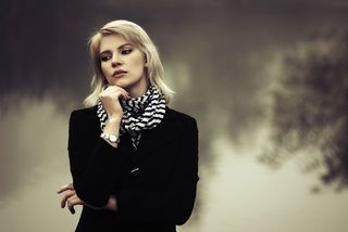 A woman stands against a foggy morning landscape