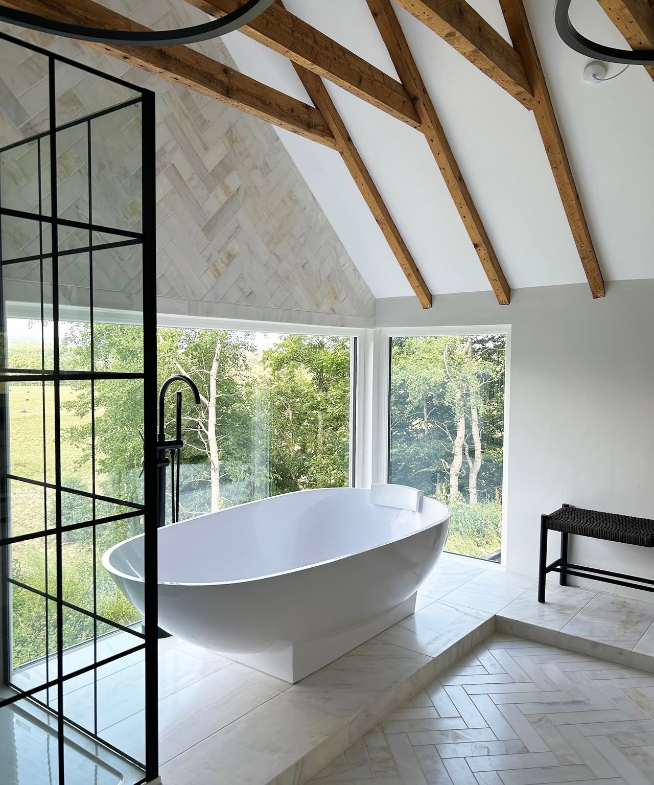 A bath in a wooden beamed room next to a large window