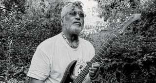 A black-and-white photo of P-Funk legend Michael Hampton with his Guyatone, in amongst heavy foliage.
