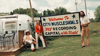 DeWolff standing outside the Muscle Shoals town sign