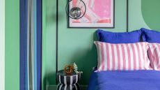 Mint green coloured bedroom with black and white striped rug and nightstand, bright blue bedding and a pendant light hung above.