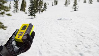 A skier holds an avalanche beacon during training